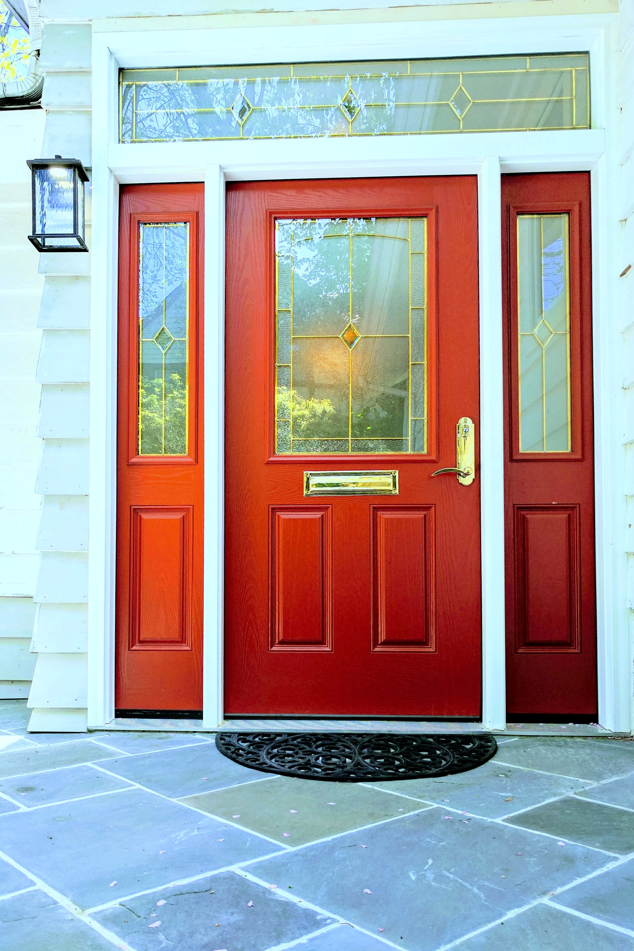 Red front door with sidelights and transom over slate porch